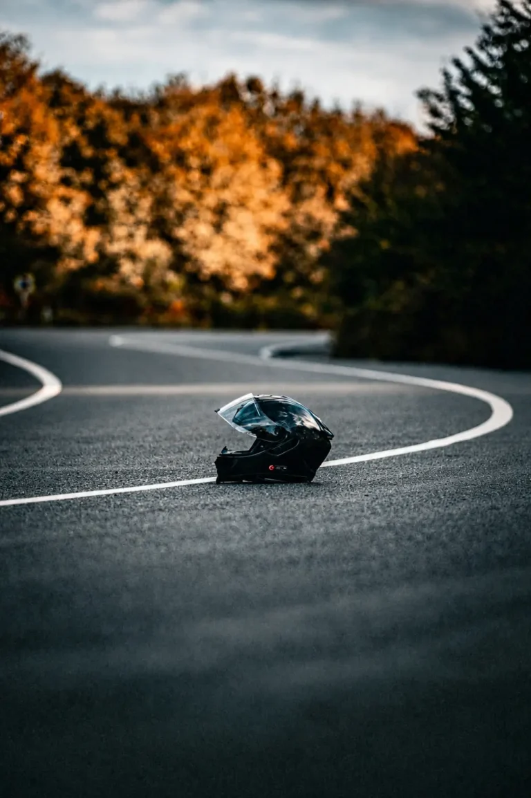 Motorradhelm im Vordergrund welcher auf der Straße in einer Kurve liegt