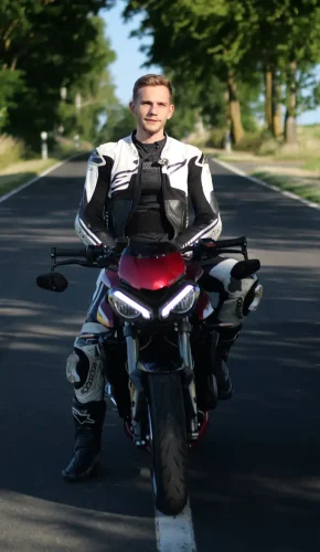 Triumph Motorrad und Fahrer in weißer Lederkombi - Gründer von Kurvenbalance Samuel Engel im Motorradalltag