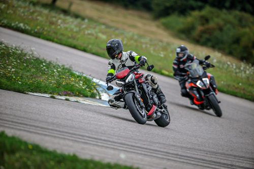 Motorrad Instruktor fährt vorweg, während der Teilnehmer hinter ihm fährt und den Fahrstil Legen übt. Beide schauen weit in die Kurve